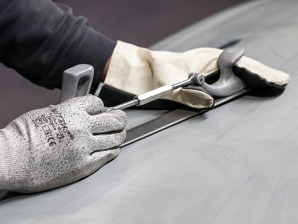 Manual processing of a metal prototype – fine adjustment and surface finishing Close-up of manual prototype processing using a file and precision tools